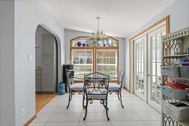 dining room with arched walkways, baseboards, a notable chandelier, and french doors