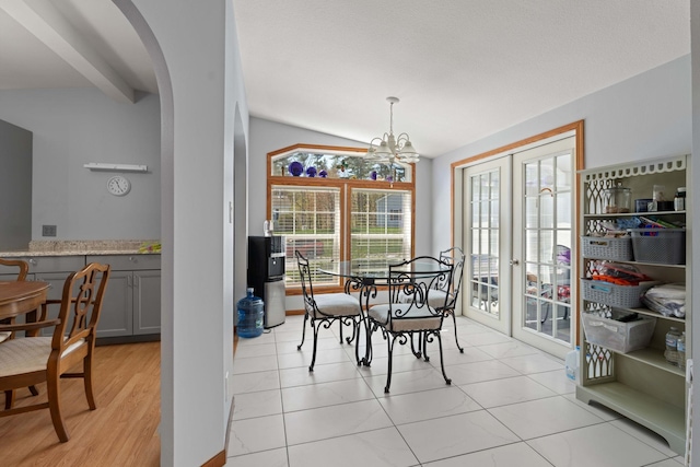 dining area with french doors, arched walkways, lofted ceiling, and a notable chandelier