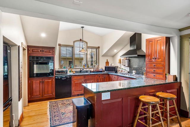 kitchen featuring a peninsula, wall chimney exhaust hood, light wood-style flooring, backsplash, and black appliances
