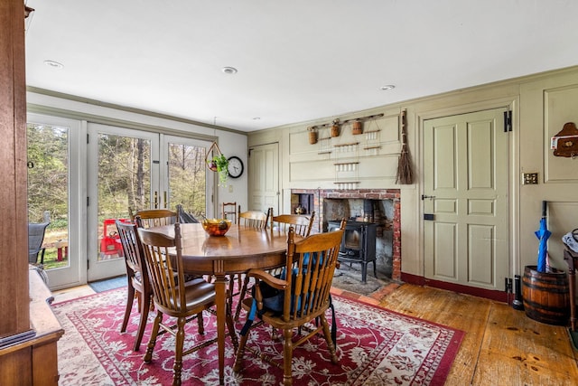 dining space featuring french doors, ornamental molding, a wood stove, and light wood-type flooring