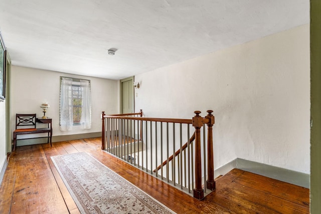 hall with an upstairs landing and hardwood / wood-style flooring