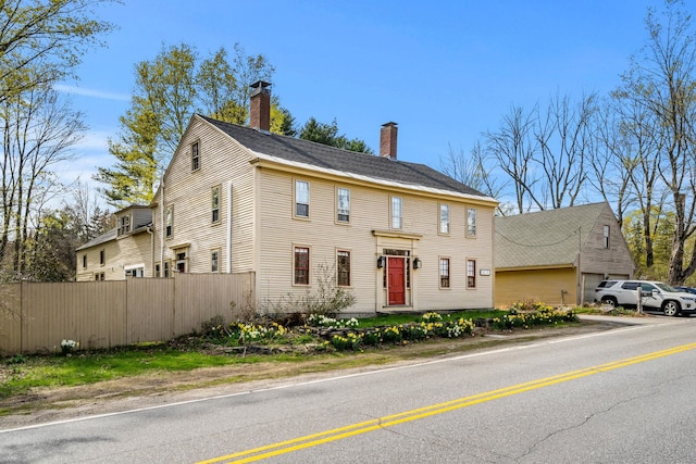 colonial-style house with fence and a chimney