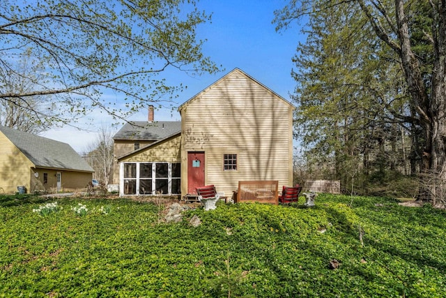 rear view of house featuring a chimney and a sunroom