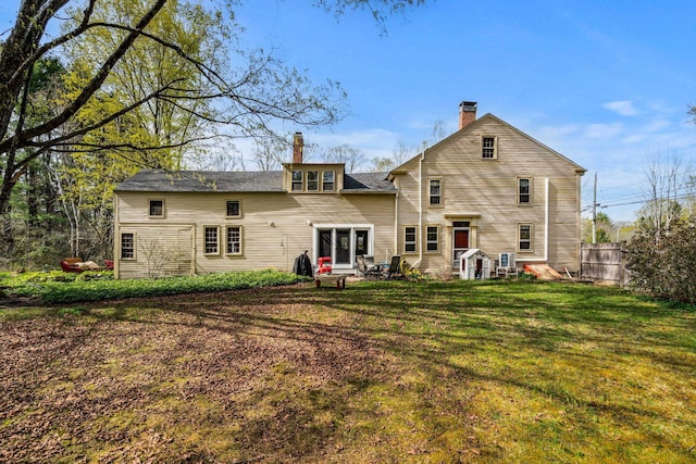 back of property with fence, a yard, and a chimney