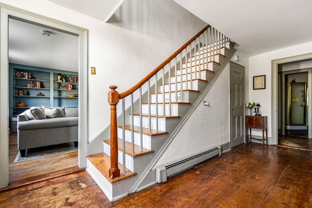 staircase featuring wood-type flooring, a baseboard radiator, and built in shelves
