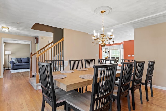 dining room with stairway, baseboards, light wood-style flooring, and a chandelier