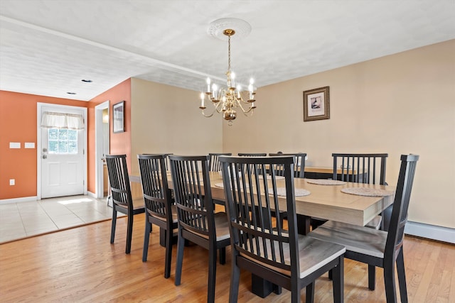 dining room featuring an inviting chandelier, baseboards, and light wood-type flooring
