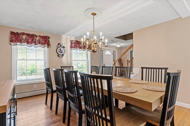 dining space with stairway, baseboards, a baseboard radiator, light wood finished floors, and a chandelier