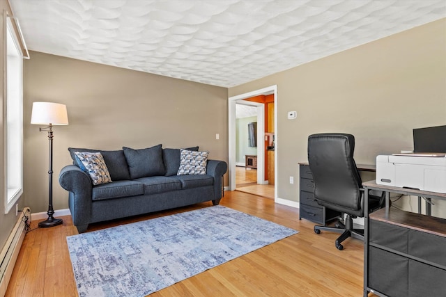 office area featuring baseboards, light wood finished floors, and a baseboard heating unit