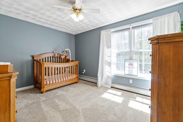 bedroom with carpet, a nursery area, multiple windows, and baseboard heating