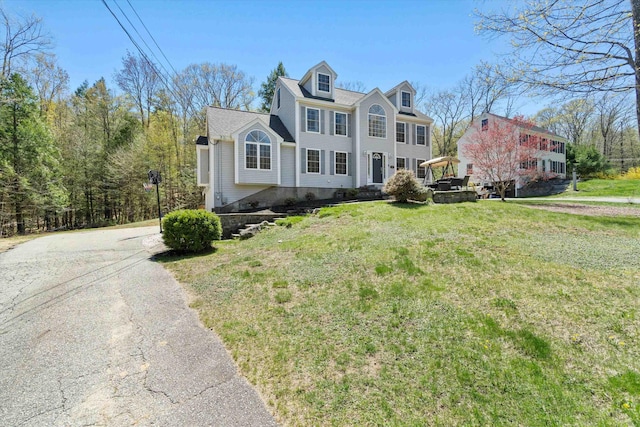 colonial inspired home with driveway and a front yard