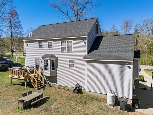 rear view of house featuring stairway, a deck, and a shingled roof