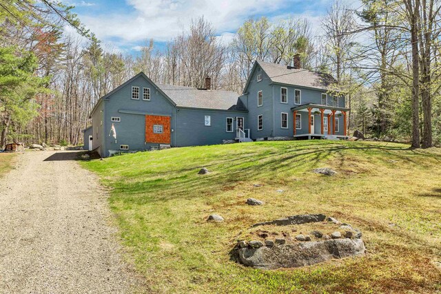 view of front facade with a front lawn, driveway, and a chimney