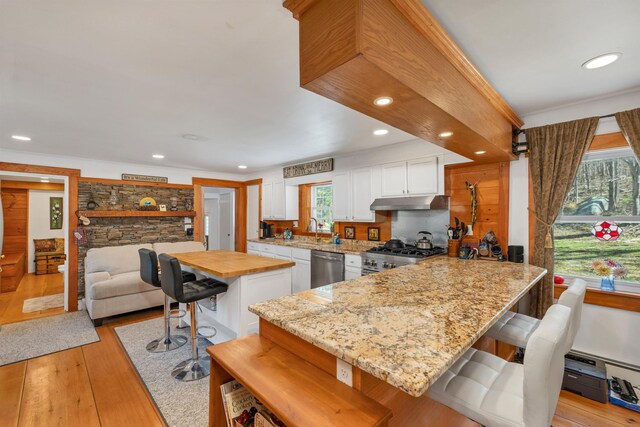 kitchen with a kitchen breakfast bar, appliances with stainless steel finishes, a sink, white cabinets, and light wood-style floors