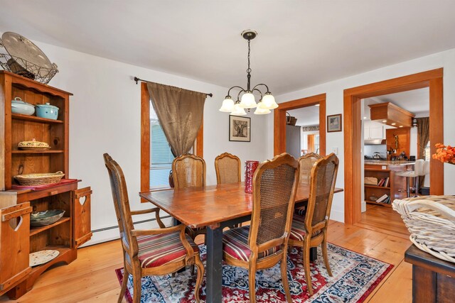 dining room featuring baseboard heating, an inviting chandelier, and light wood-style flooring