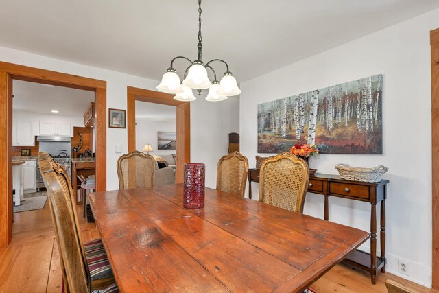 dining space featuring light wood-type flooring and a notable chandelier