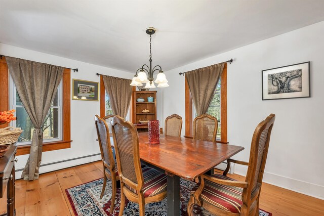 dining space featuring a healthy amount of sunlight, baseboards, light wood-type flooring, and a notable chandelier