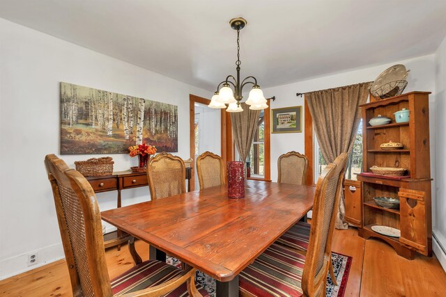 dining space with light wood-style flooring and a notable chandelier