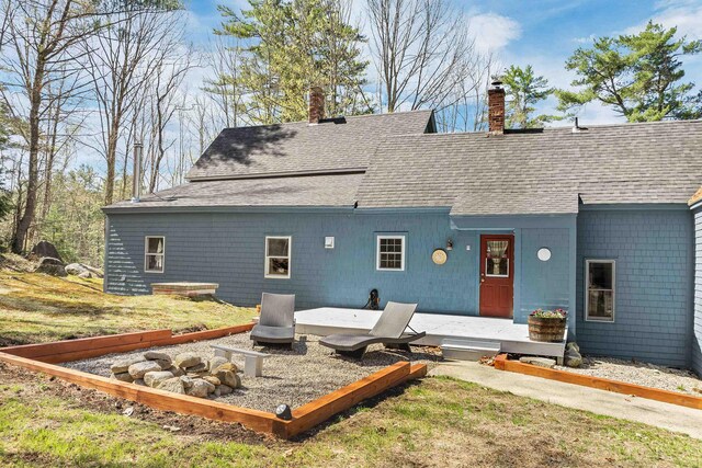 back of property with a yard, a chimney, and a shingled roof