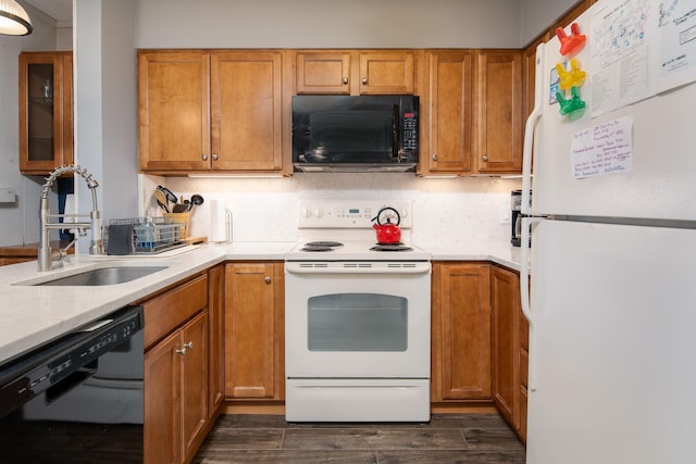 kitchen with brown cabinets, dark wood finished floors, a sink, and black appliances