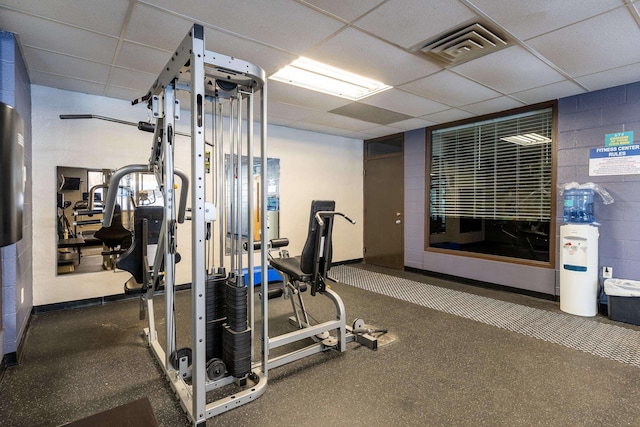 gym with concrete block wall, a drop ceiling, and visible vents