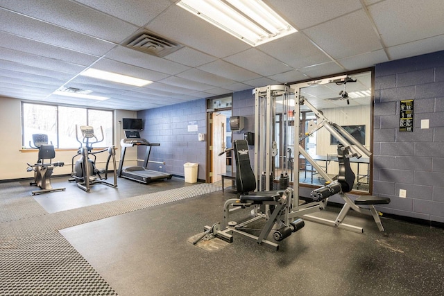 workout area with concrete block wall, a drop ceiling, and visible vents