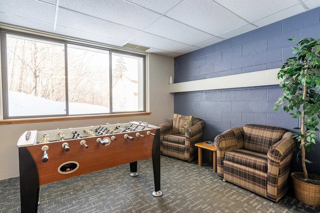 rec room with carpet flooring, a drop ceiling, and concrete block wall