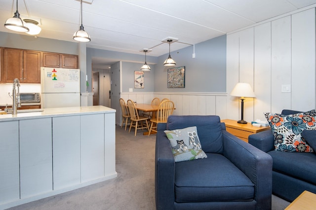 living area featuring a toaster, wainscoting, and light colored carpet