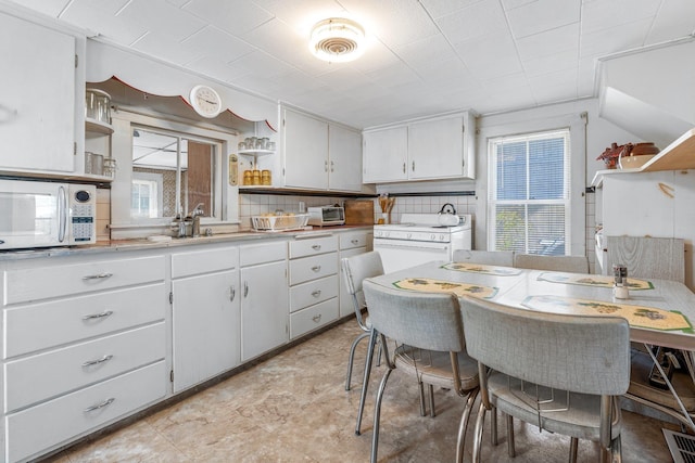 kitchen featuring white appliances, open shelves, a wealth of natural light, and light countertops