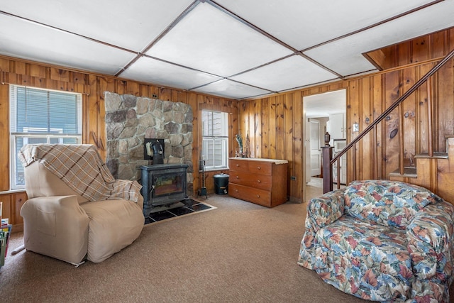 living area featuring stairway, a wood stove, and wood walls