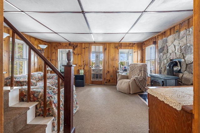 bedroom with wood walls, carpet, multiple windows, and a wood stove