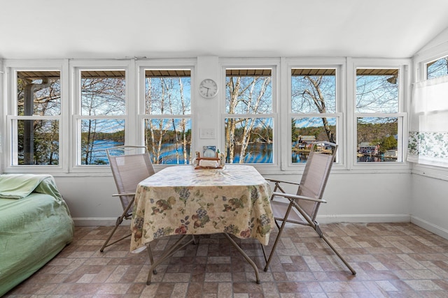 sunroom with baseboards, a water view, and brick patterned floor