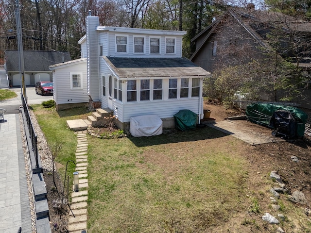 rear view of house with a chimney, an outbuilding, a yard, a shingled roof, and entry steps