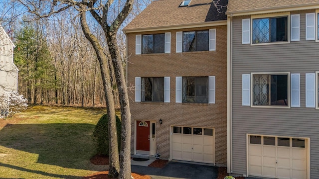 townhome / multi-family property with driveway, roof with shingles, a garage, brick siding, and a front lawn