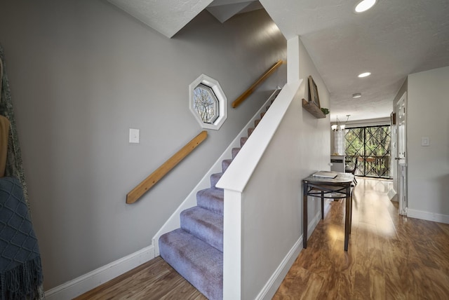 stairs with recessed lighting, baseboards, wood finished floors, and a textured ceiling