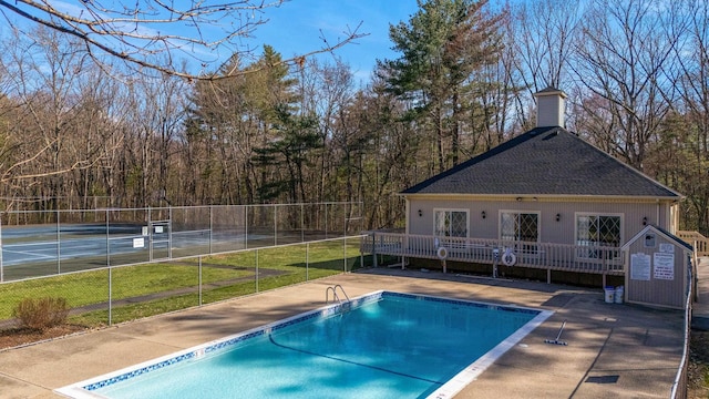 pool with fence, an outdoor structure, and a tennis court