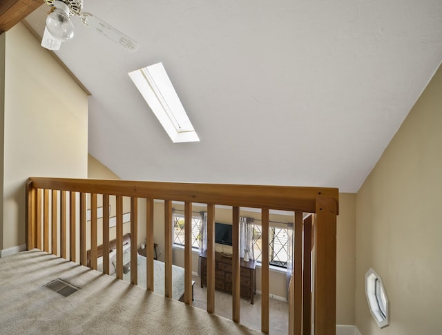 staircase with a ceiling fan, visible vents, baseboards, lofted ceiling with skylight, and carpet