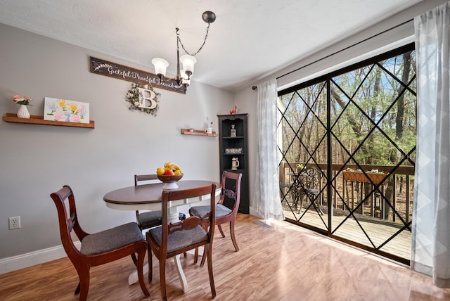 dining room with baseboards, wood finished floors, and a chandelier