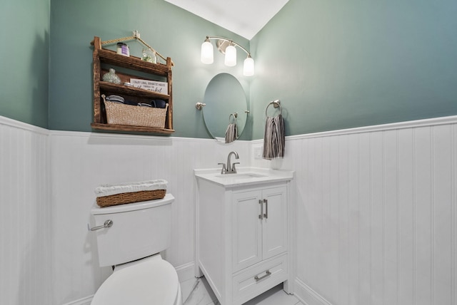 bathroom featuring toilet, wainscoting, and vanity