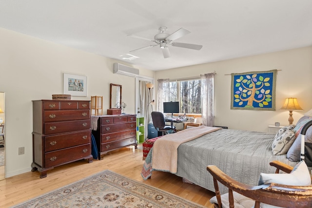 bedroom with an AC wall unit, ceiling fan, and light wood-type flooring