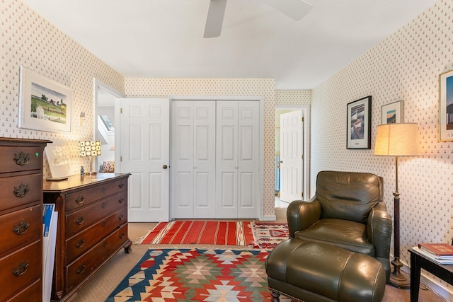 living area featuring a ceiling fan, wallpapered walls, and carpet
