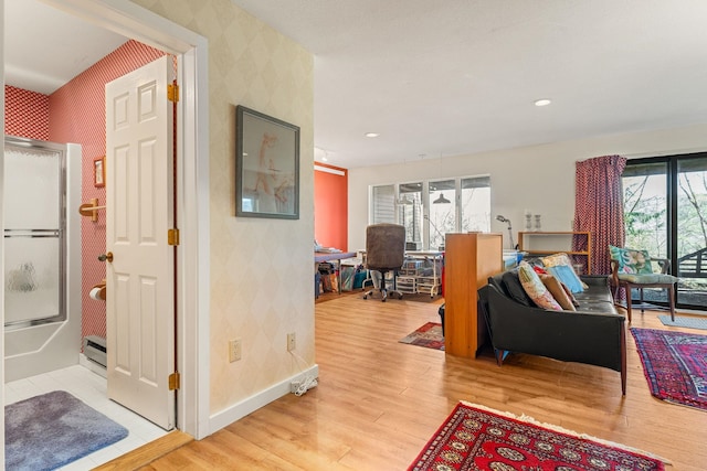 living area featuring light wood-style floors, baseboards, and wallpapered walls