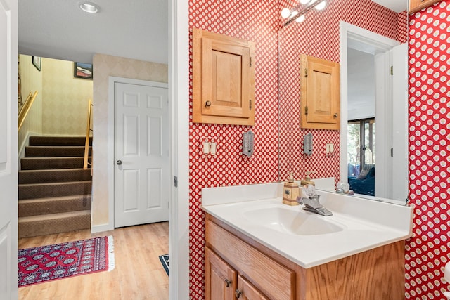 bathroom featuring vanity, wallpapered walls, and wood finished floors