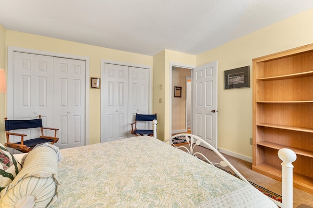 bedroom with two closets, baseboards, and carpet