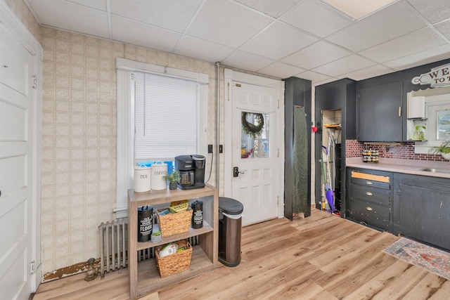 kitchen with light countertops, a drop ceiling, light wood-type flooring, and a sink