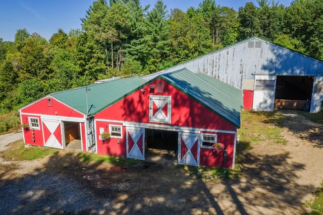 view of barn with driveway and a forest view