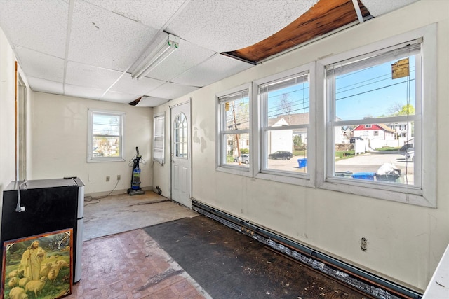 exercise room featuring a paneled ceiling and a baseboard heating unit