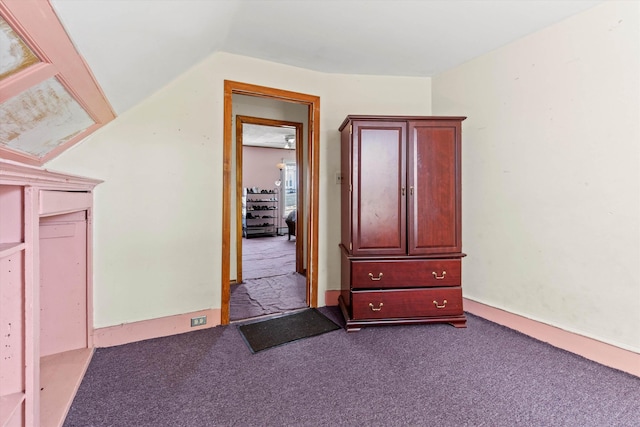 unfurnished bedroom with vaulted ceiling and dark colored carpet