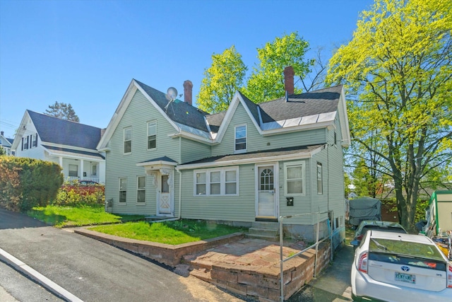 view of front of property with a shingled roof, entry steps, and a chimney
