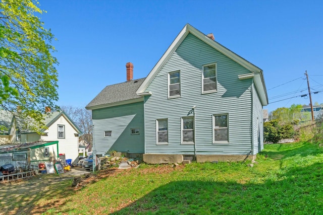 rear view of property with a yard and a chimney